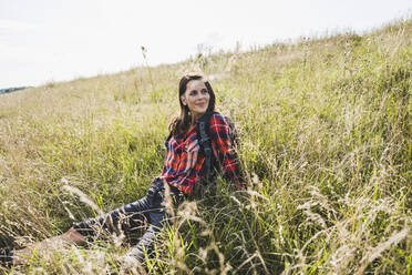 Wanderin, die sich im Gras sitzend ausruht - UUF24288