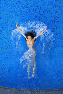 Junge Frau spritzt beim Schwimmen im Pool mit Wasser - EAF00033