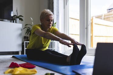 Flexible Frau berührt ihre Zehen beim Training zu Hause - WPEF05096