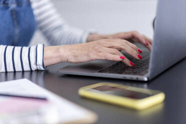 Weibliche Fachkraft tippt auf einem Laptop im Heimbüro - WPEF05119