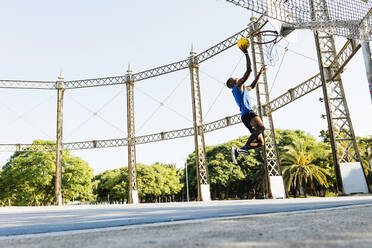 Male basketball player scoring basket at sports court - XLGF02126