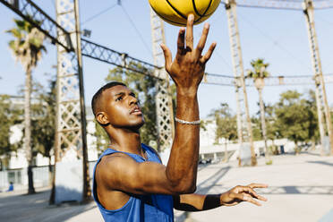 Man spinning basketball on finger at sports court - XLGF02130