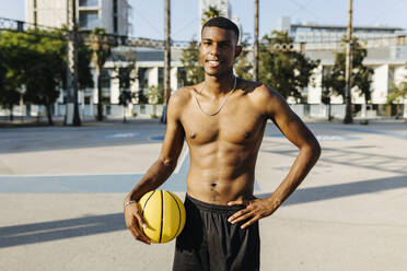 Männlicher Basketballspieler mit Hand auf der Hüfte auf einem Sportplatz - XLGF02141