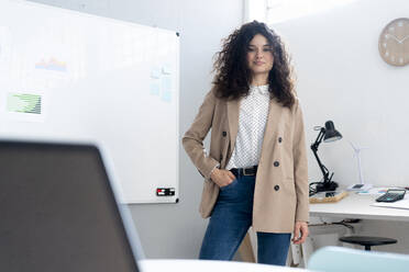 Confident businesswoman with hands in pockets standing in office - GIOF13084