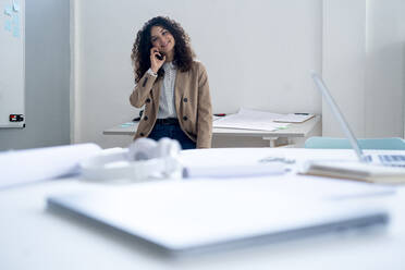 Smiling businesswoman talking on mobile phone at desk - GIOF13089