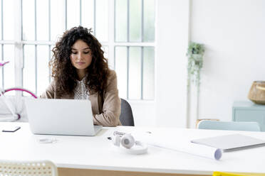 Junge Geschäftsfrau arbeitet am Laptop am Schreibtisch im Büro - GIOF13095
