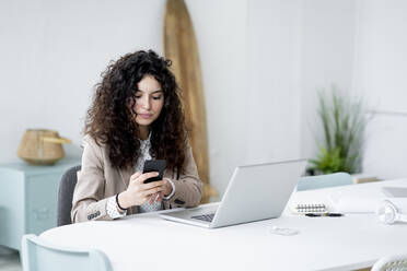 Businesswoman using mobile phone while working in office - GIOF13103