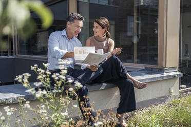 Business professionals having discussion over document in front of office building - UUF24309