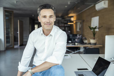 Businessman sitting by laptop on desk - UUF24389