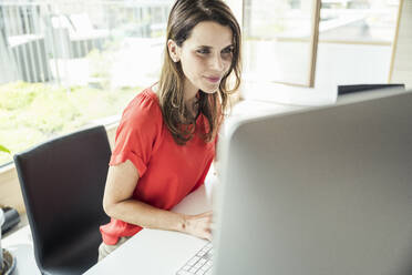 Weibliche Fachkraft, die einen Computer am Schreibtisch im Büro benutzt - UUF24406