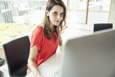 Geschäftsfrau starrt beim Sitzen am Computer-Schreibtisch im Büro - UUF24407