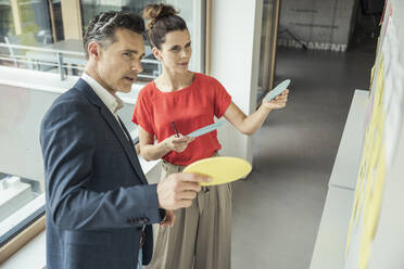 Männliche und weibliche Fachkräfte diskutieren über Whiteboard im Büro - UUF24412