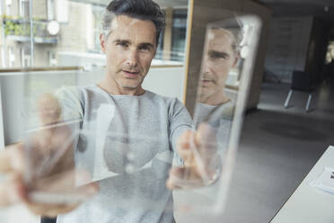 Businessman checking glass model in office - UUF24437