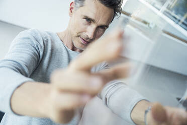 Businessman checking glass box while working at office - UUF24439