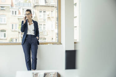 Weibliche Fachkraft, die im Büro mit einem Smartphone telefoniert - UUF24452