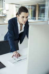Weibliche Fachkraft, die einen Computer am Schreibtisch im Büro benutzt - UUF24456