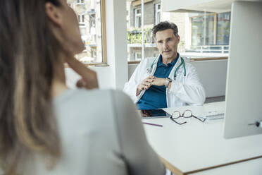 Male doctor discussing with female patient in office - UUF24474