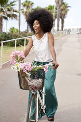 Cheerful young woman riding bicycle on road - VEGF04793