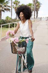 Fröhliche junge Frau fährt mit dem Fahrrad auf der Straße - VEGF04793