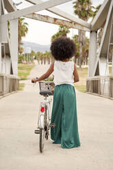 Afro woman with bicycle walking on bridge - VEGF04802