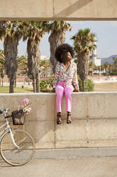 Woman sitting on wall by bicycle - VEGF04805