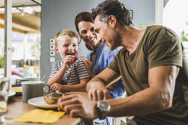 Fröhliche Familie beim gemeinsamen Frühstück zu Hause - UUF24494