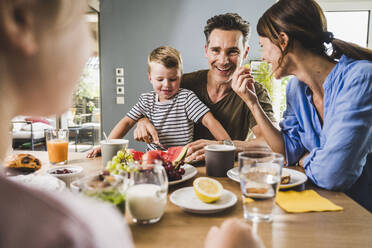 Happy family eating fruits during breakfast at home - UUF24496