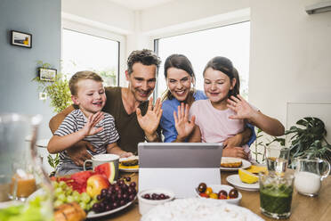 Family greeting while doing video call on digital tablet at home - UUF24503