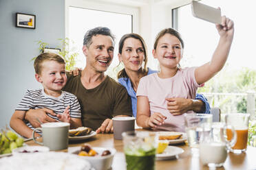 Mädchen nimmt Selfie mit Familie durch Smartphone zu Hause - UUF24507