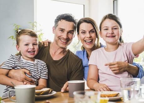 Glückliche Familie, die zu Hause den Arm umeinander legt - UUF24509