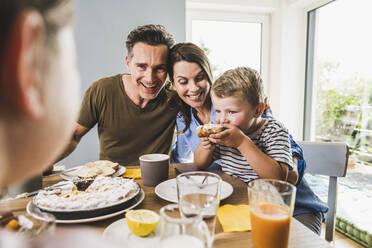 Mann mit Frau sieht Sohn beim Frühstück Kuchen essen - UUF24512