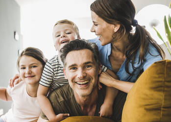 Woman looking at son while playing with sofa at home - UUF24520