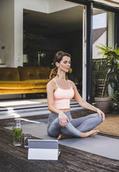 Woman meditating while exercising on terrace - UUF24590