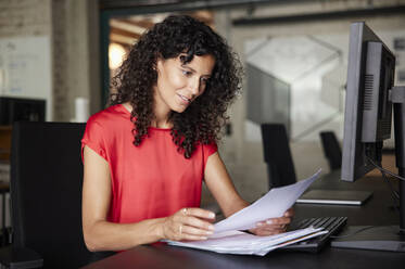 Geschäftsfrau beim Lesen eines Dokuments während der Arbeit im Büro - RBF08219