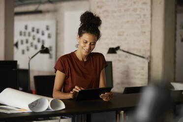 Weiblicher Berufstätiger mit digitalem Tablet am Schreibtisch im Büro - RBF08289