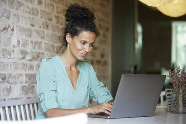 Berufstätige Frau benutzt Laptop bei der Arbeit im Büro - RBF08291