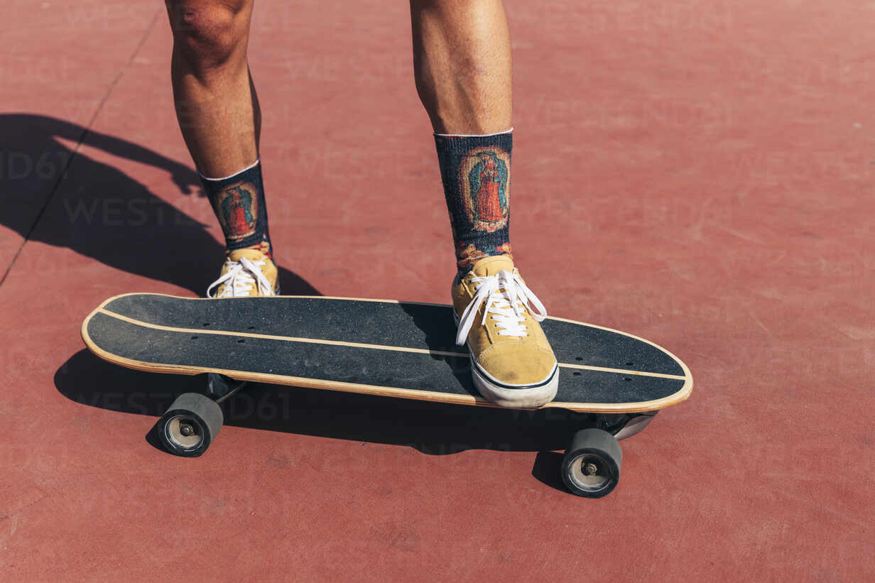 Young man skateboarding at basketball court on sunny day stock photo