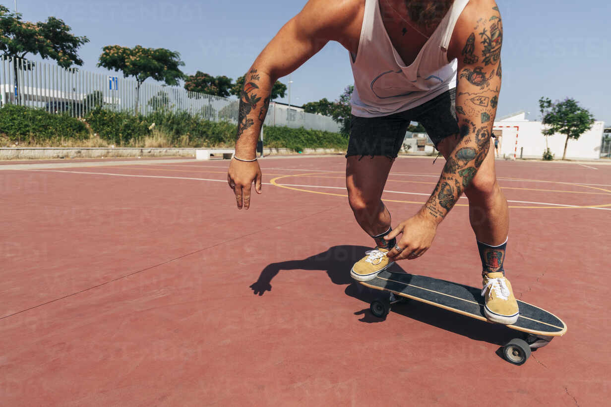 Young man skateboarding at basketball court during sunny day stock