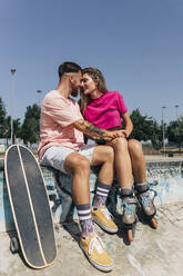 Junges Paar sitzt sich in einem Skateboard-Park an einem sonnigen Tag gegenüber - JRVF01381