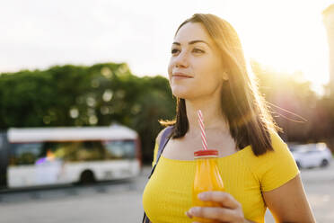 Junge Frau mit Saftflasche auf der Straße - XLGF02148