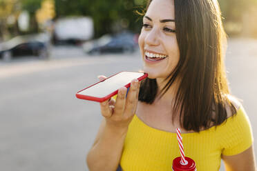 Happy young woman talking on mobile phone at street - XLGF02150