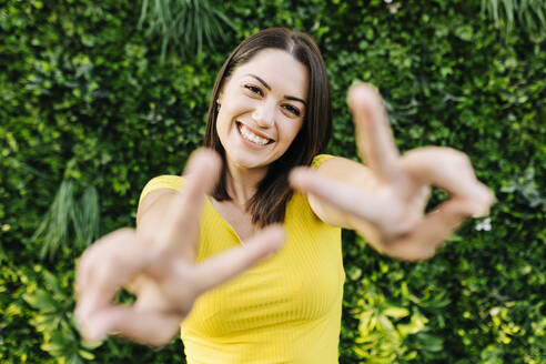 Happy young woman gesturing peace sign - XLGF02153