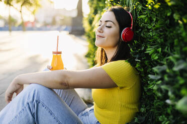 Junge Frau hört mit geschlossenen Augen Musik über Kopfhörer - XLGF02161