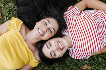 Happy lesbian couple lying together on grass at park - TCEF02060