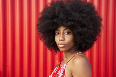 Afro junge Frau an roter Wellblechwand - VEGF04812