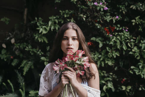 Beautiful young woman with flowers in front of ivy plants - DSIF00537