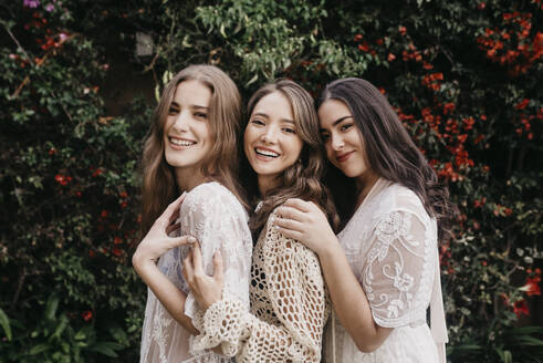 Lächelnde junge Frauen, die zusammen bei Pflanzen stehen - DSIF00540