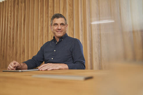 Smiling male professional sitting with digital tablet in board room - AKLF00365