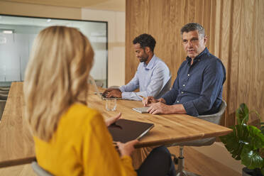 Male and female colleagues discussing during meeting at office - AKLF00389