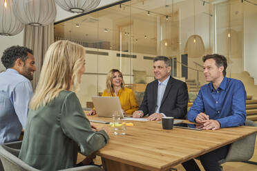 Businessman having discussion with colleagues in meeting at board room - AKLF00423